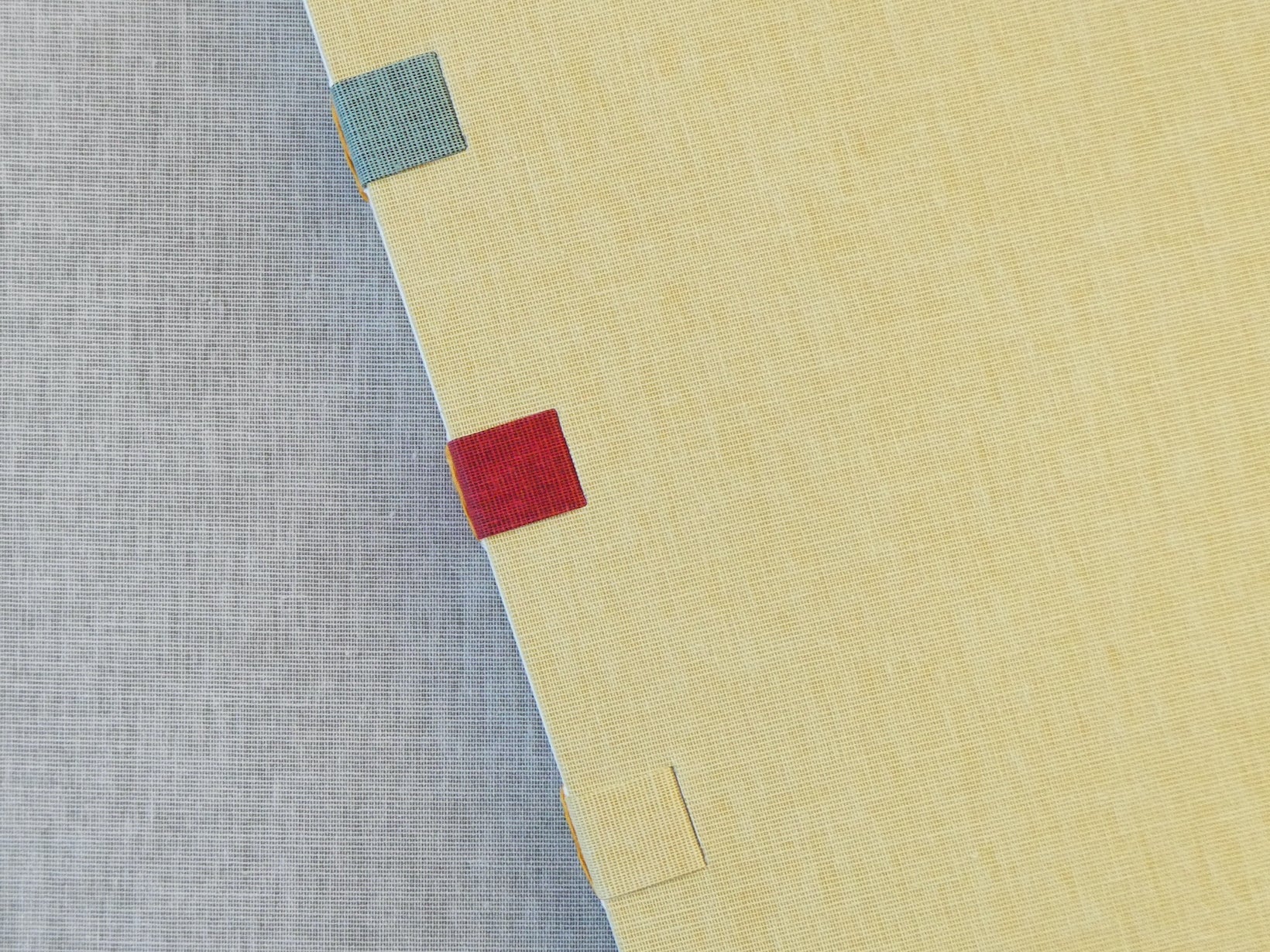 Textured fabric book covers with colourful square patches on a beige and gray background