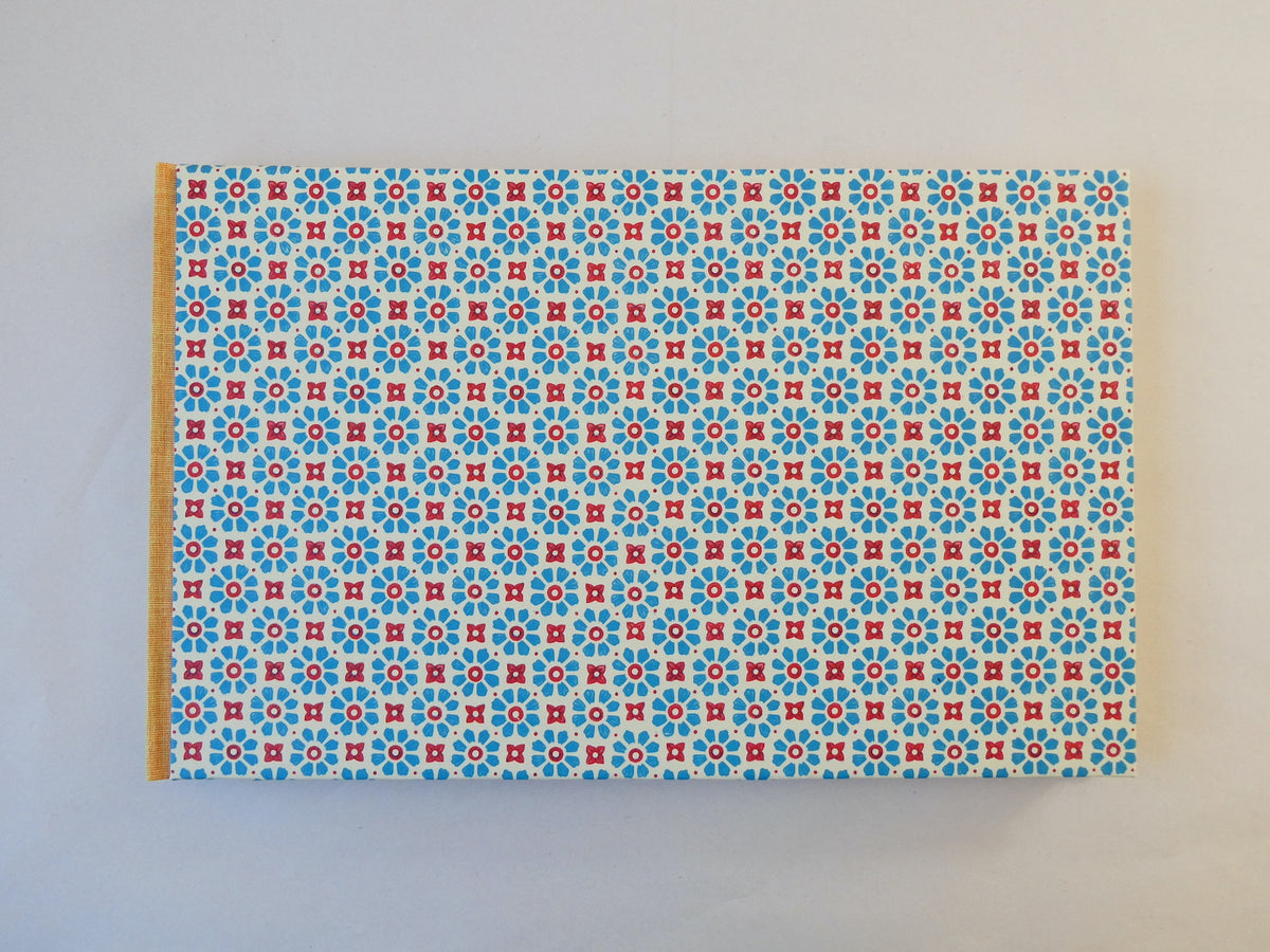 Handmade sketchbook with blue and red Italian patterned paper cover on a white background