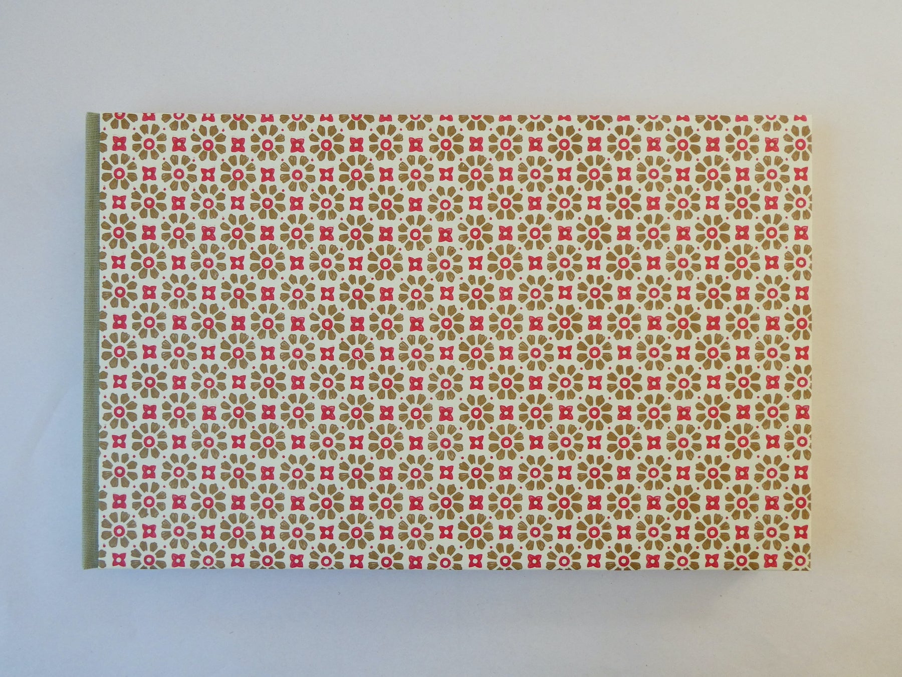 Handmade sketchbook with red and gold Italian patterned paper cover on a white surface