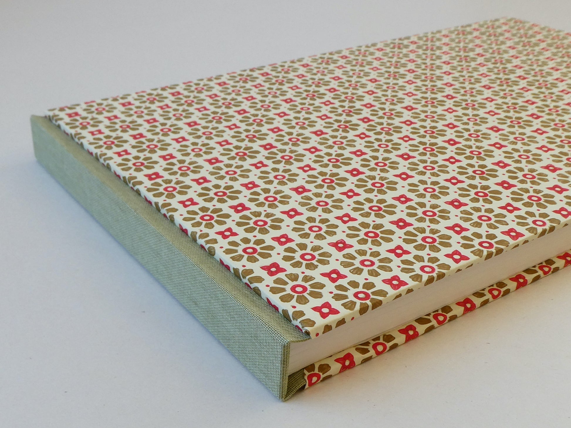 Sketchbook with a red and gold floral patterned cover on a white background