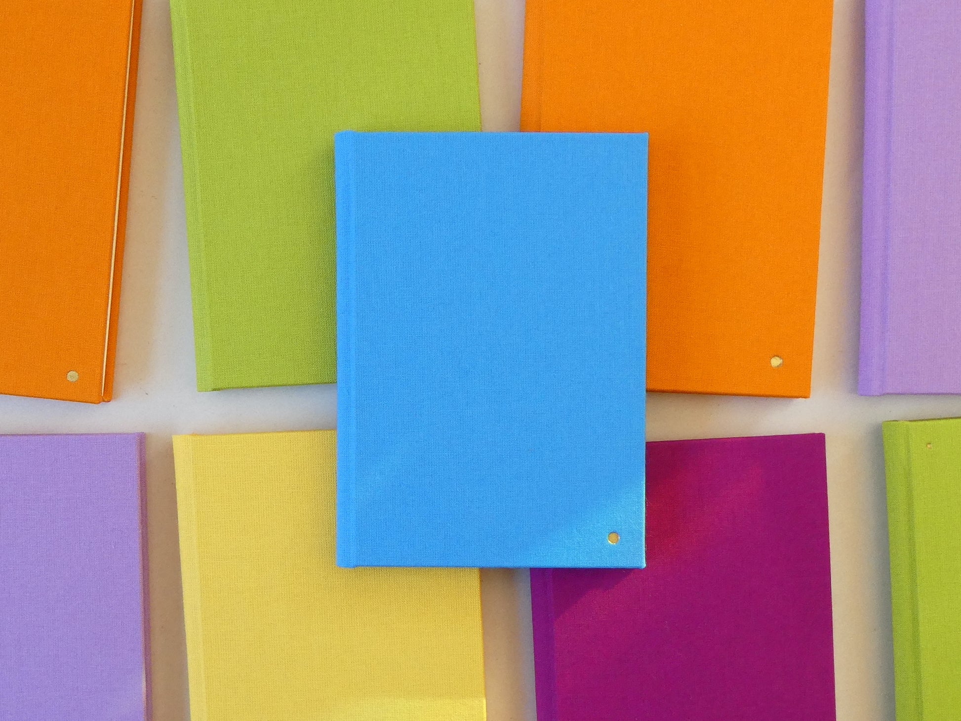 Colourful notebooks arranged in a grid pattern on a light background