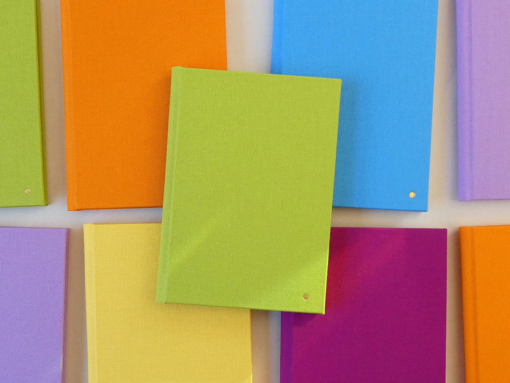 Colourful sketchbooks arranged in a grid pattern on a white background