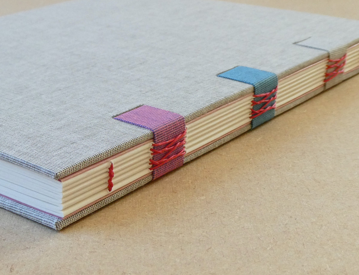 Book with colorful woven spine on a beige surface