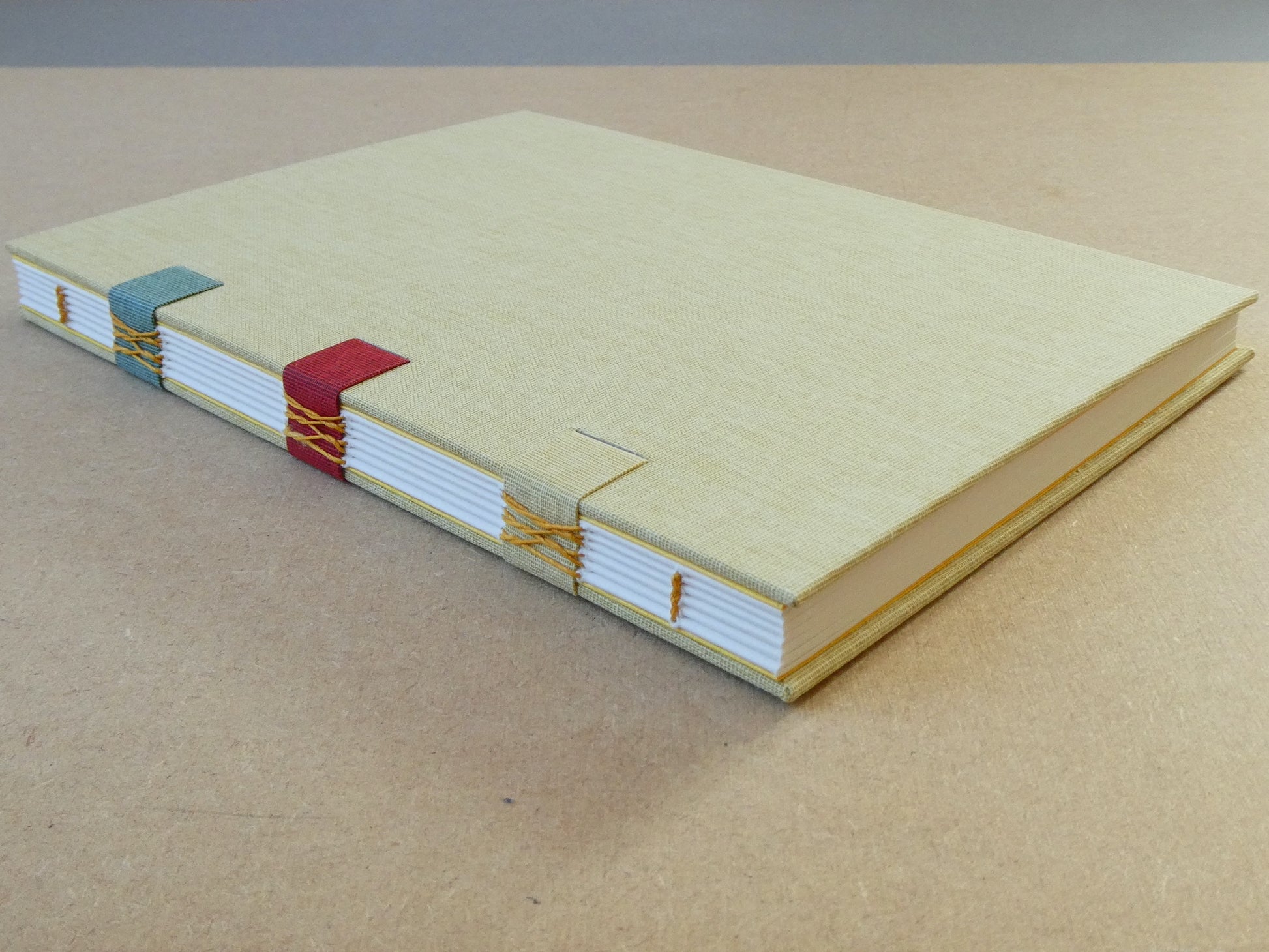 Handmade sketchbook with colourful binding on a beige surface