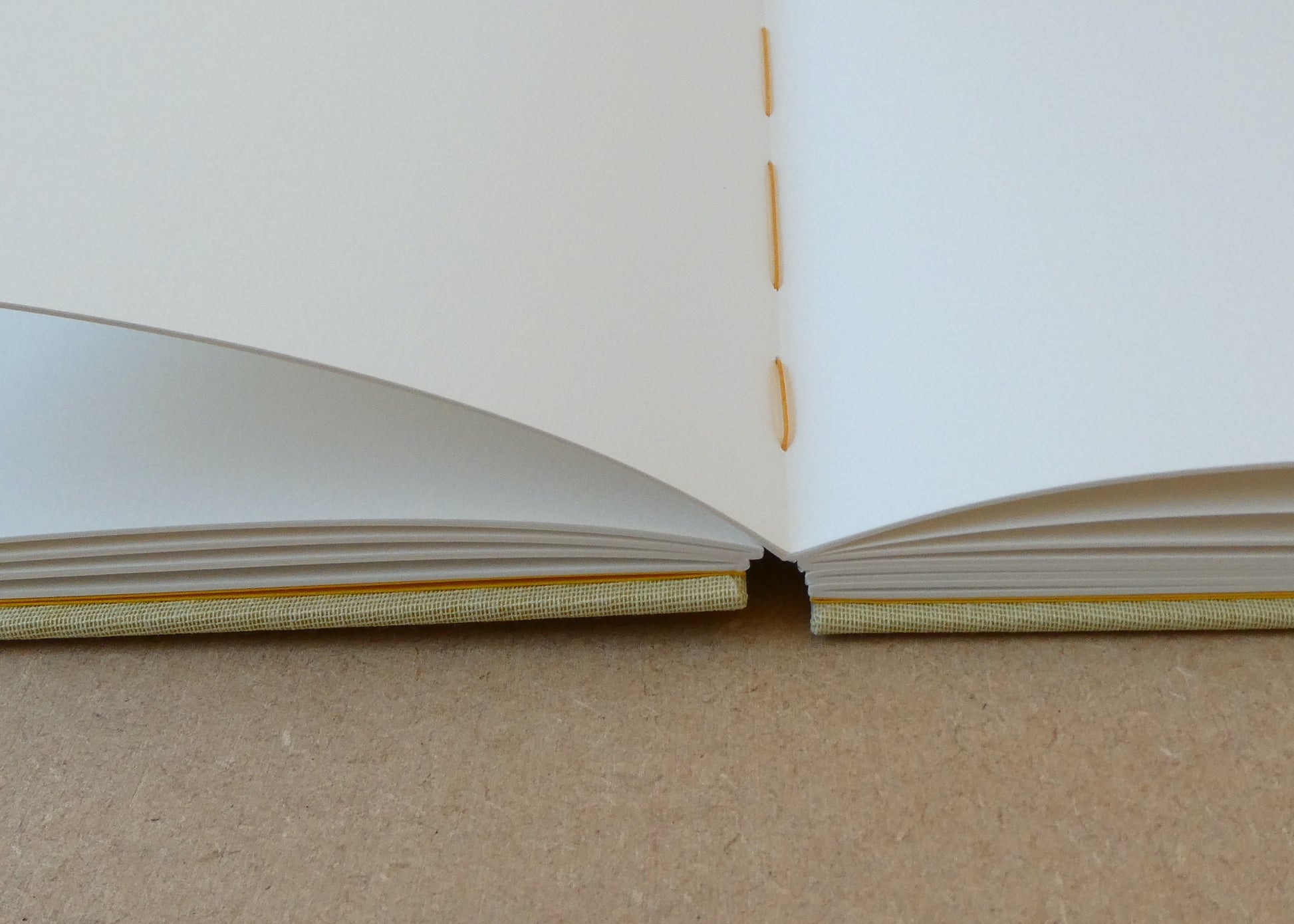 Open book with white pages and gold binding on a beige surface