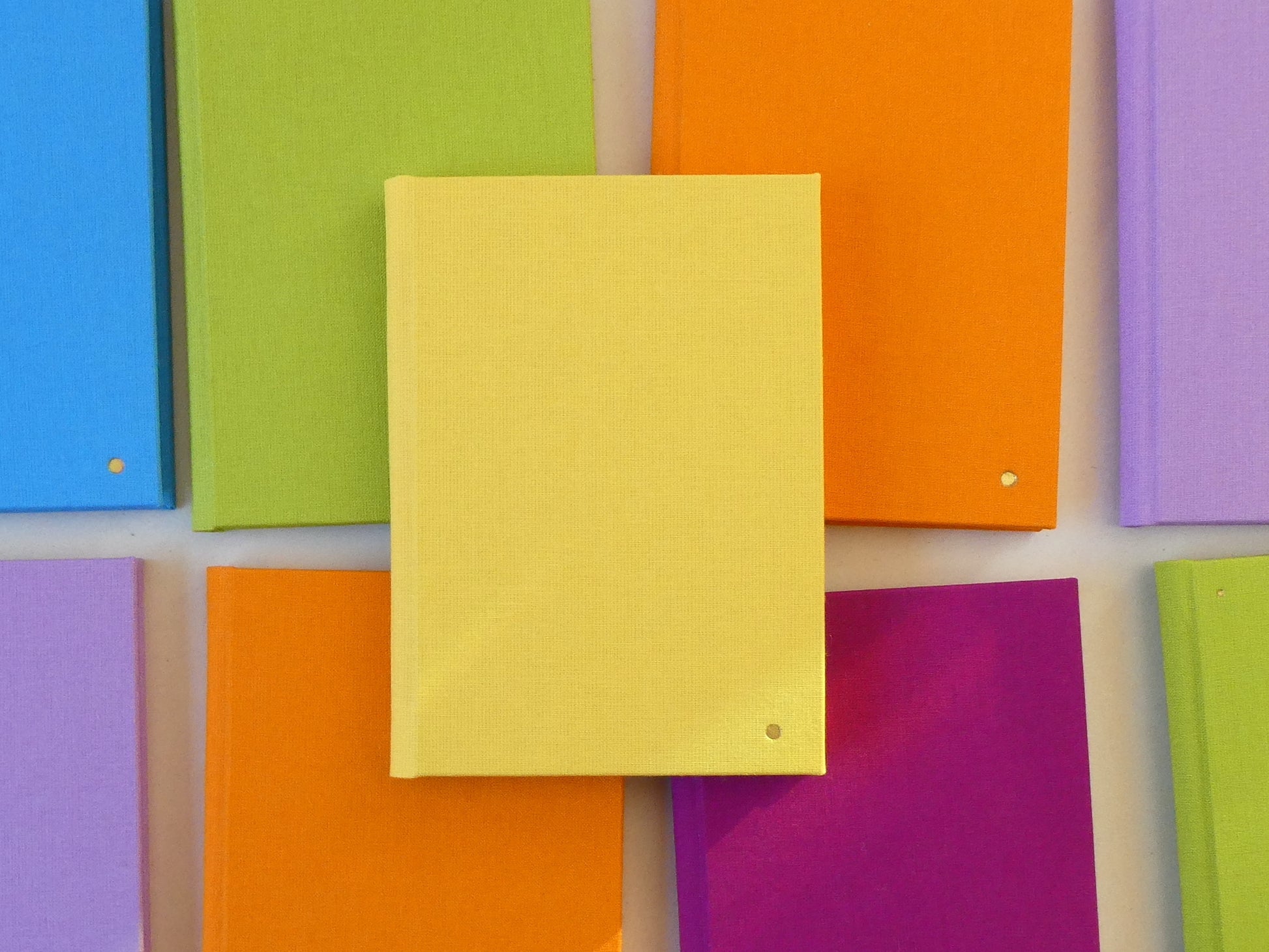 Colourful notebooks arranged in a grid pattern on a white background