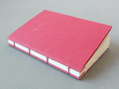 Handmade pink notebook with white pages on a gray background