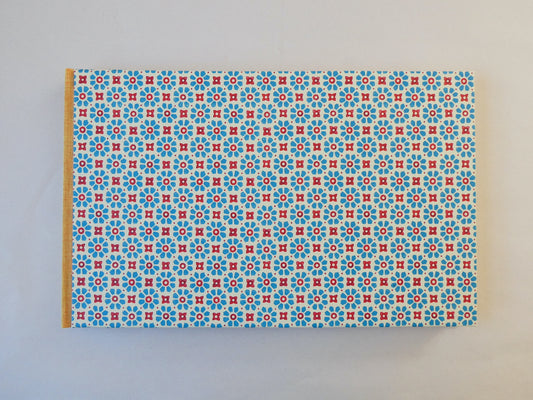 Handmade sketchbook with blue and red Italian patterned paper cover on a white background
