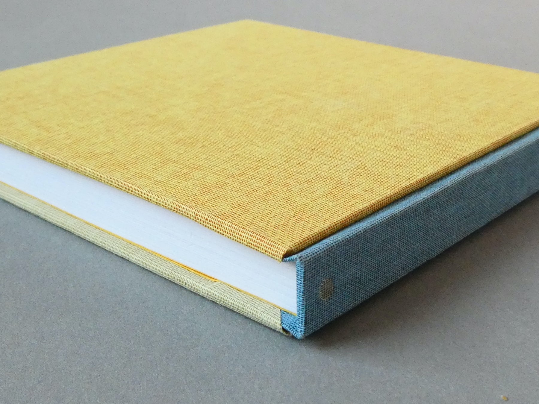 Hand bound sketchbooks with a blue spine on a gray surface