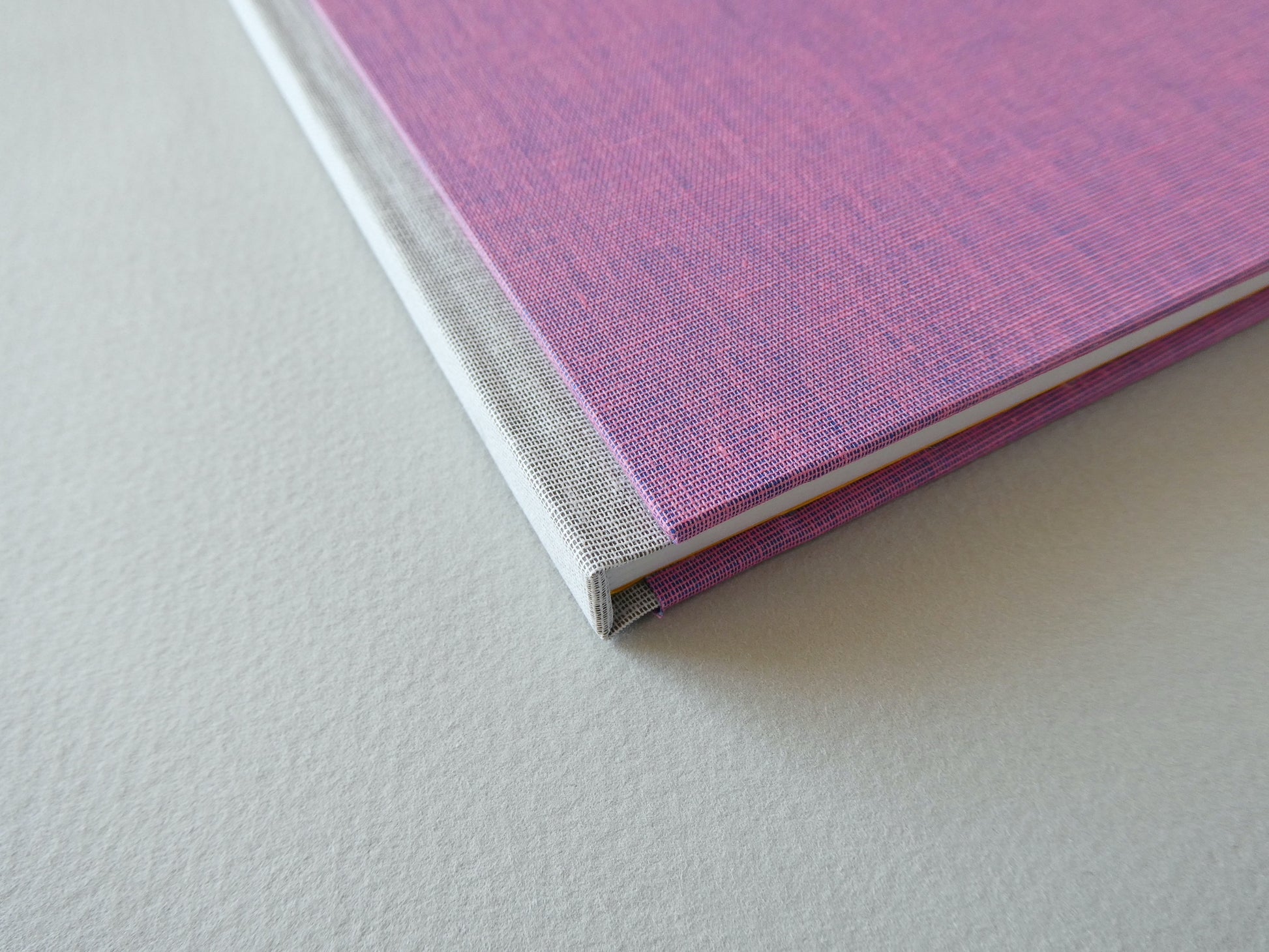 Close-up of a pink hand bound sketchbook on a light grey surface