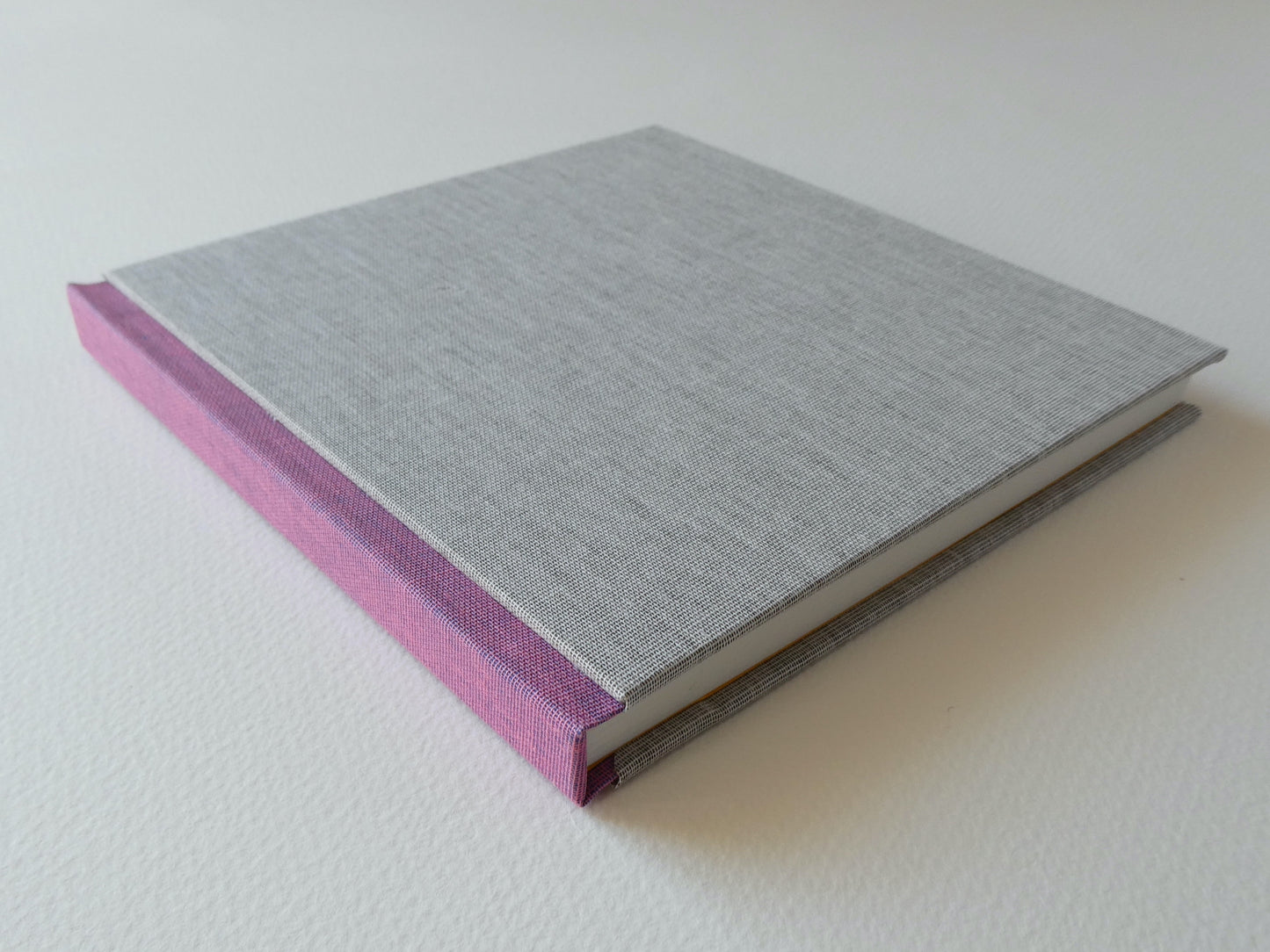 Grey handbound sketchbook with pink spine on a white background