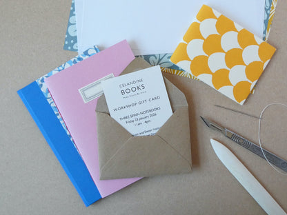 Workshop gift card in a brown envelope with colourful notebooks and tools on a brown surface